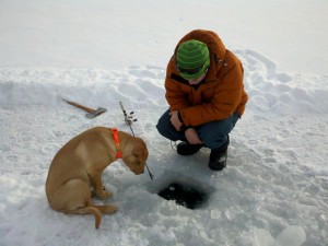 Drew Hollinger and his nephew Henry (the dog) peer into an ice fishing hole on Echo Lake.